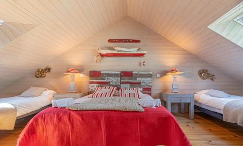 une chambre mansardée avec deux lits et une couverture rouge dans l'établissement L'Atelier d'artiste by Domaine de Colomban - plages et commerces à pieds, à Carnac