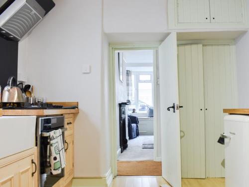 a kitchen with a door leading to a hallway at Brook Cottage in Dawlish