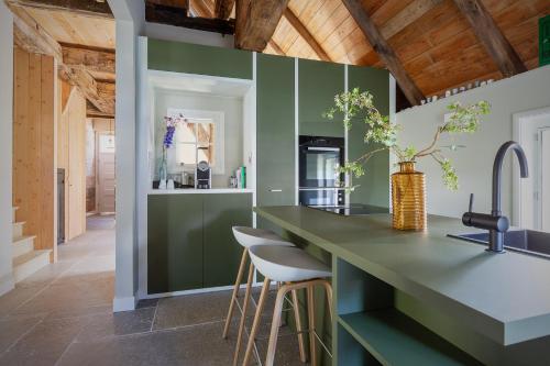 a kitchen with green walls and a counter with stools at Malle Mühle Bed & Breakfast in Lage