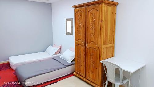 a room with two beds and a wooden cabinet at Aziz House 1 in Tan-Tan