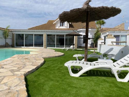 a yard with two lawn chairs and an umbrella at Chalet Albariza in Sanlúcar de Barrameda