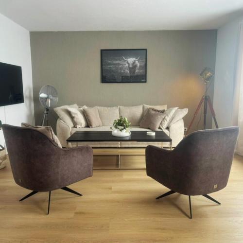 a living room with a couch and two chairs at FACT Apartments in Arnoldstein