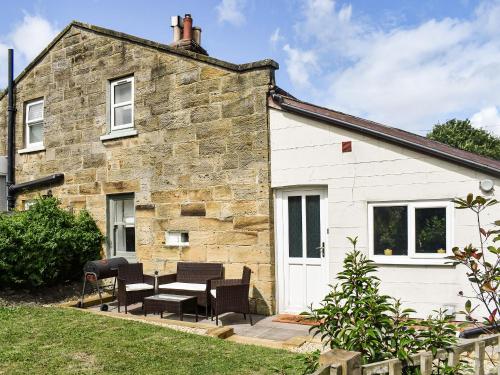 a stone house with black chairs and a patio at Chapel Cottage in Robin Hood's Bay