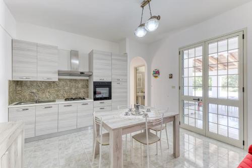a kitchen with white cabinets and a table and chairs at Salentoandmore - Smeralda Onda Blu in Marina di Pescoluse