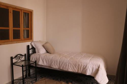 a small bed in a room with a window at Dar margoum in Marrakech