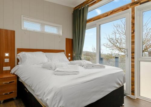 a bedroom with a bed with white sheets and a window at Cheddar Woods Resort And Spa in Cheddar