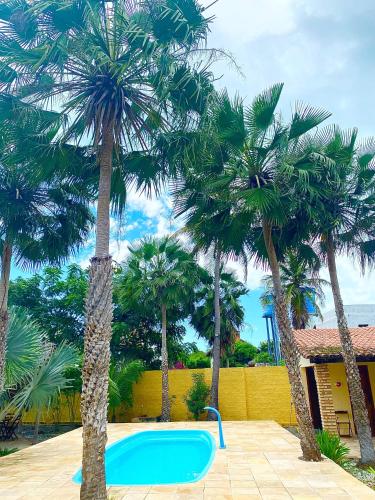 a swimming pool with palm trees in a yard at Pousada e Chalés Recantos do Mar in Barra Grande