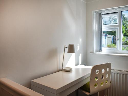 a white desk with a lamp and a chair in a room at Wylandre in Amlwch