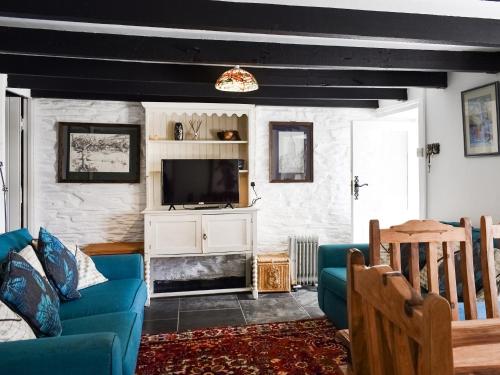 a living room with a blue couch and a tv at Barn Cottage - Uk47089 in Davidstow