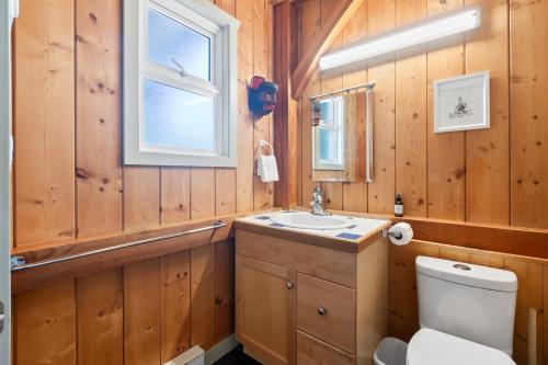 a bathroom with wooden walls and a toilet and a sink at Bear Coast, Cabin with Hot Tub, Patio, and Waterview in Ucluelet