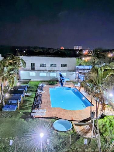 a swimming pool at night with a resort at Pousada das Estrelas Atibaia in Atibaia