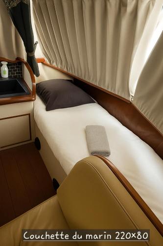 Ce lit se trouve dans une petite chambre dotée d'un ordinateur portable. dans l'établissement Bateau le Zimon - logement insolite, à Rouen