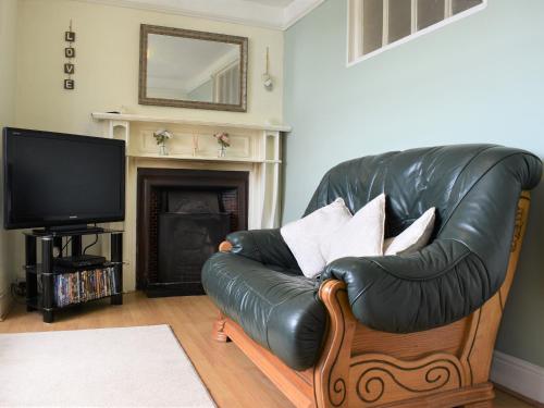 a leather couch in a living room with a television at Scenery Cottage in Bridford