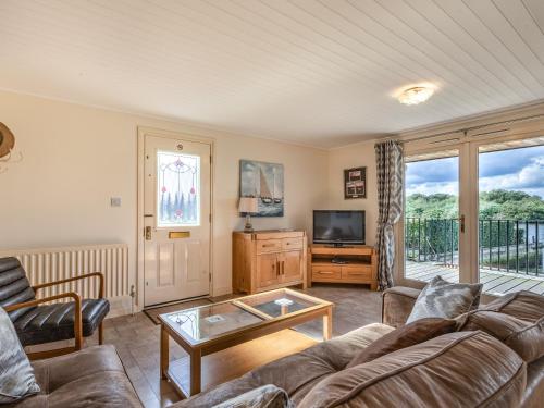 a living room with a couch and a tv at Sunset Lodge in Brundall