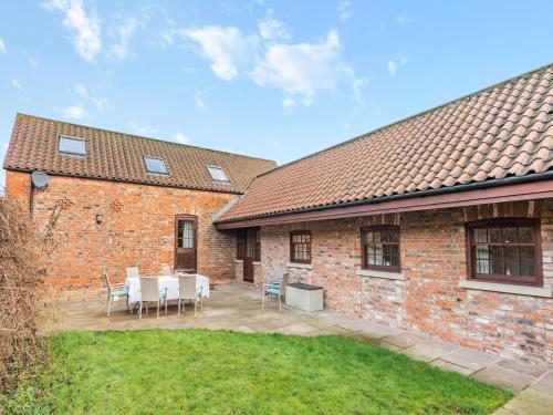 a brick house with a patio with a table and chairs at The Old Combine Shed in Huby
