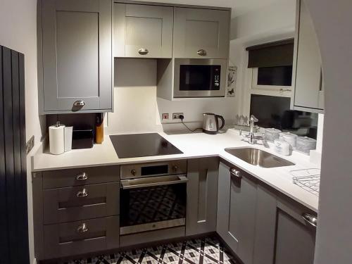a kitchen with gray cabinets and a sink at Stable Cottage in Alnwick
