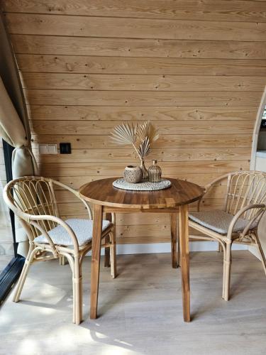 a wooden table with two chairs and a wooden wall at Tiny House De Bosksjonger in Westergeest