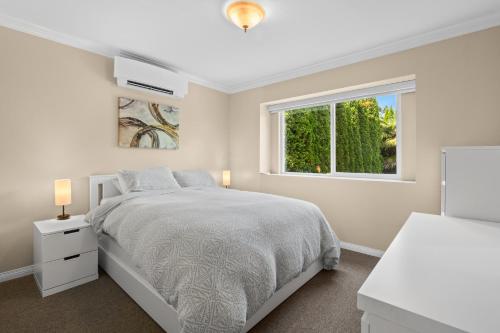 a white bedroom with a bed and a window at Luxury Retreat in Vancouver in Vancouver