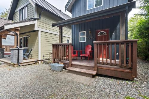 a house with a deck with red chairs on it at Bear Coast, Cabin with Hot Tub, Patio, and Waterview in Ucluelet