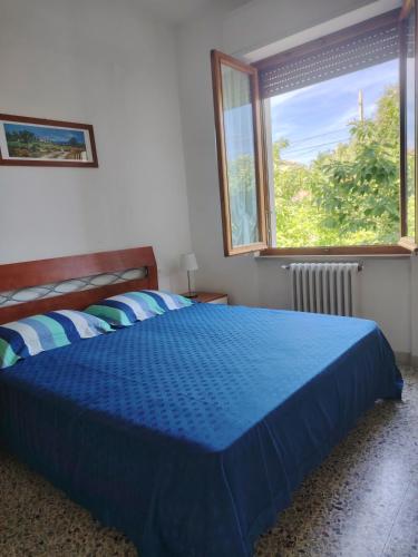 ein blaues Bett in einem Schlafzimmer mit einem Fenster in der Unterkunft Casa di Caterina in Castiglioncello