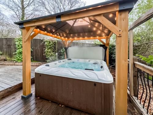 bañera de hidromasaje bajo un cenador en una terraza en Whydown Cottage, en Hooe