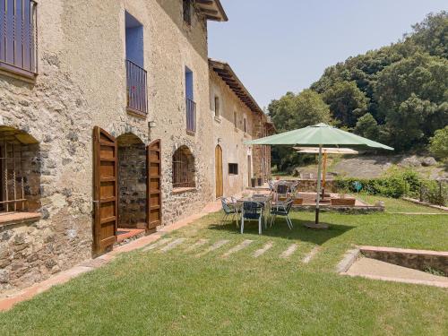 a patio with an umbrella and a table and chairs at Aiguabella - Allotjaments Rurals in Sant Felíu de Pallarols