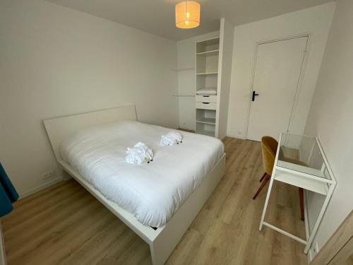 - une petite chambre avec un lit blanc et une table en verre dans l'établissement Plein coeur de Caen, Emeraude, à Caen