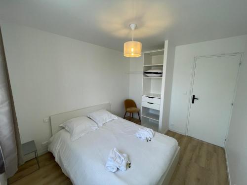 une chambre avec un lit blanc avec des serviettes dessus dans l'établissement Plein coeur de Caen, Emeraude, à Caen