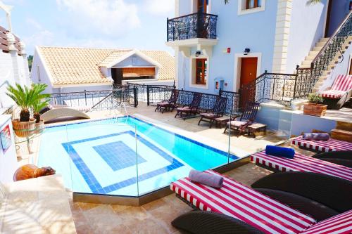 a swimming pool with lounge chairs and a house at Faros Suites (Adults Only) in Fiskardo