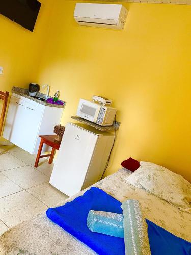 a room with a bed and a microwave on a yellow wall at Pousada e Chalés Recantos do Mar in Barra Grande