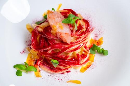 a plate of food with red peppers and shrimp at Swiss Diamond Boutique Hotel - La Romantica in Melide