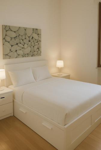 a white bed in a bedroom with two lamps at Casa Sofia in Villasimius