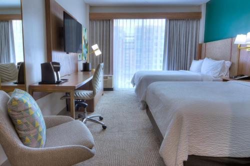 a hotel room with two beds and a desk at Holiday Inn Gainesville-University Center by IHG in Gainesville