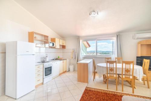 a kitchen and dining room with a table and a white refrigerator at Apartments Katarine Zrinske in Vodice