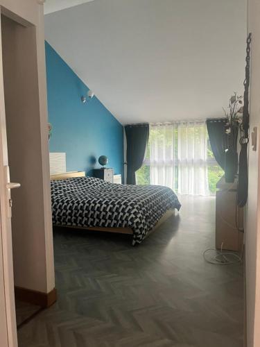 une chambre avec un lit et un mur bleu dans l'établissement Gîte du Haras du Suet, 