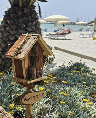 a wooden bird house with a welcome sign on it at Vel Marì - Rooms on the Beach in Alghero
