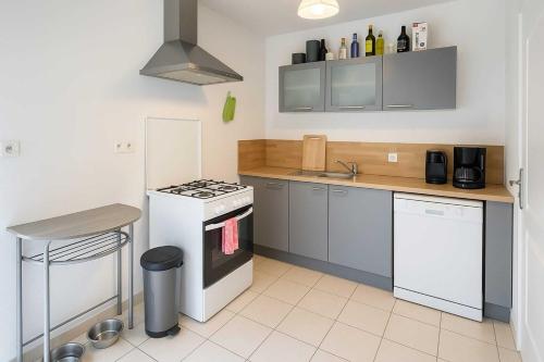 Il comprend une cuisine équipée d'une cuisinière blanche et d'un évier. dans l'établissement La Coloc des Floralies - CHAMBRE CHEZ L'HABITANT - Plage des Demoiselles - Proximité Noirmoutier - Sud Nantes, à Saint-Jean-de-Monts