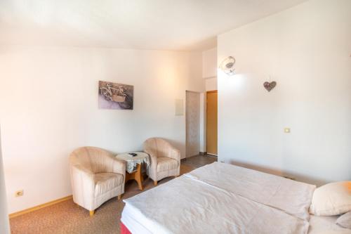 a bedroom with a bed and two chairs at Apartments Katarine Zrinske in Vodice