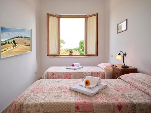 two beds in a room with a window at Casa Vacanze Santa Caterina in Asciano