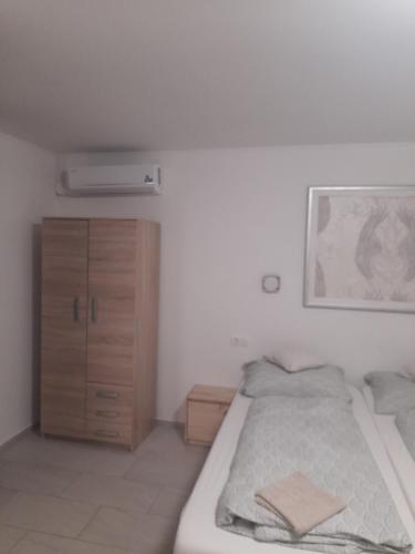 a white bedroom with a bed and a dresser at BB64 Apartmanház in Békéscsaba