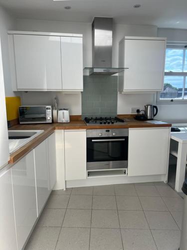a kitchen with white cabinets and a stove top oven at Modern 1 bed Blackheath Apartment in Blackheath