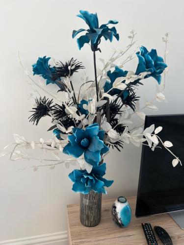 a vase filled with blue flowers on a desk at Modern 1 bed Blackheath Apartment in Blackheath