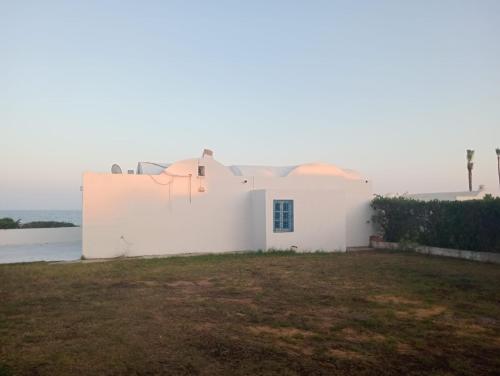 a white house with the ocean in the background at Bungalow Nabeul Mamoura in El Maamoura