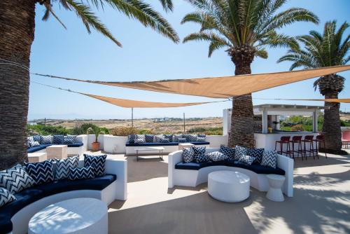 a patio with blue and white furniture and palm trees at Kallisti Paros in Naousa
