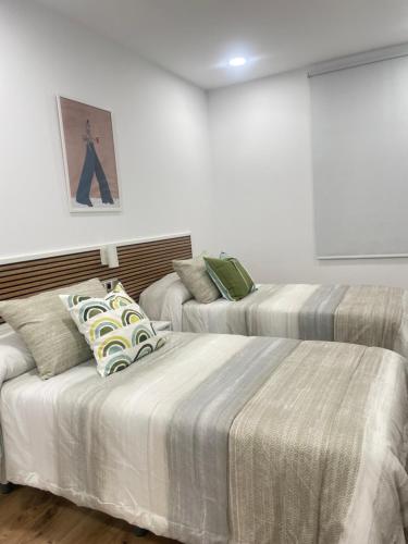 two beds in a room with white walls at Hostal Jimena restaurante el Porvenir in Martiherrero