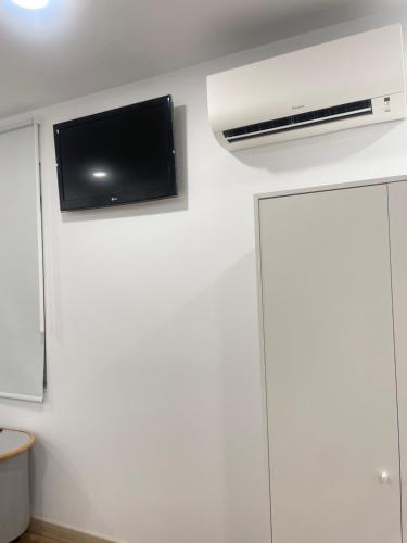 a room with a tv on a white wall at Hostal Jimena restaurante el Porvenir in Martiherrero