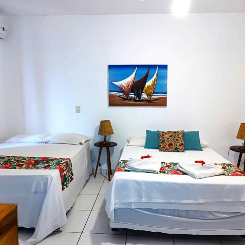 a room with two beds and a painting on the wall at Pousada Ello in São Miguel do Gostoso