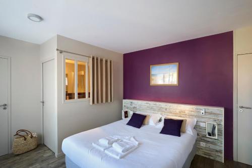 a bedroom with a large white bed with purple walls at Maison Esperanza hôtel et appartement in Noirmoutier-en-l'lle