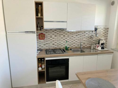 eine Küche mit weißen Schränken, einer Spüle und einem Kühlschrank in der Unterkunft Appartamento Bellavista in Roccella Ionica