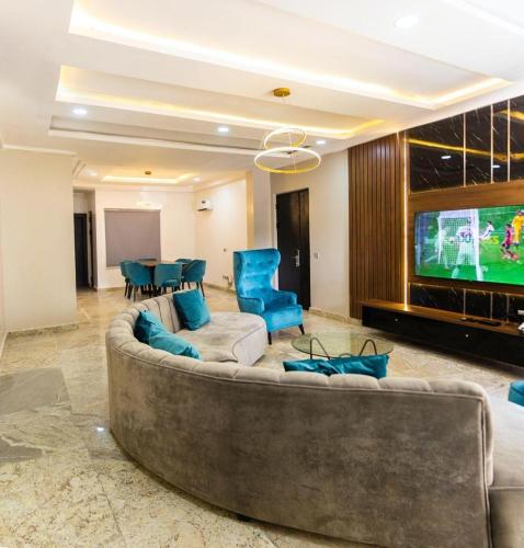 salon z dużą kanapą i telewizorem z płaskim ekranem w obiekcie Emirate Apartment w mieście Abudża